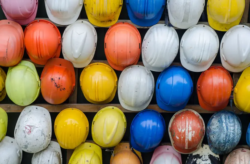 Estante con decenas de cascos de seguridad de varios colores ordenados en casilleros